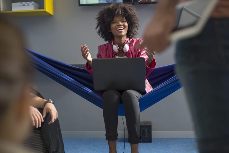 Happy woman in hammock with laptop