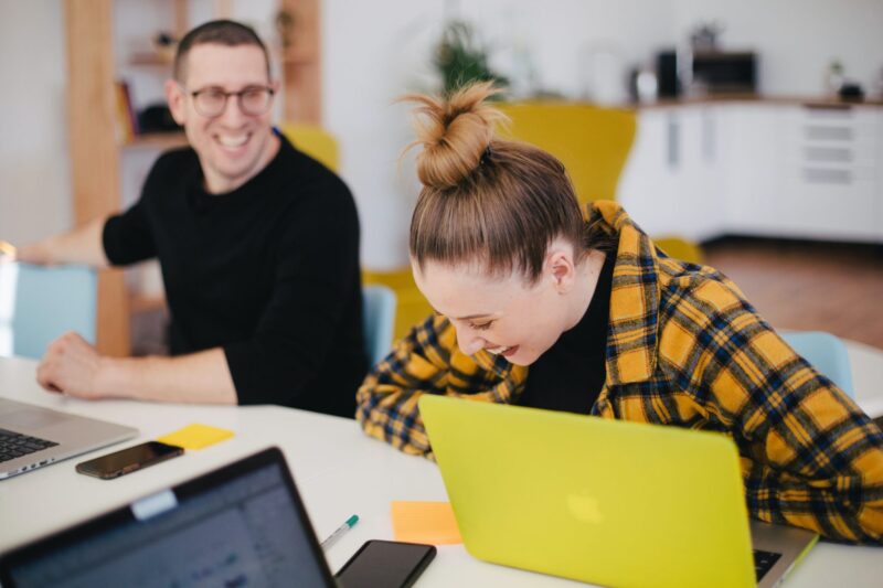 Happy man and woman laughing in front of their laptops
