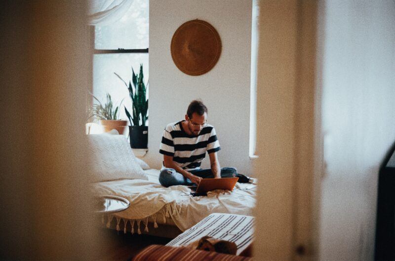 Man working on a laptop on a bed